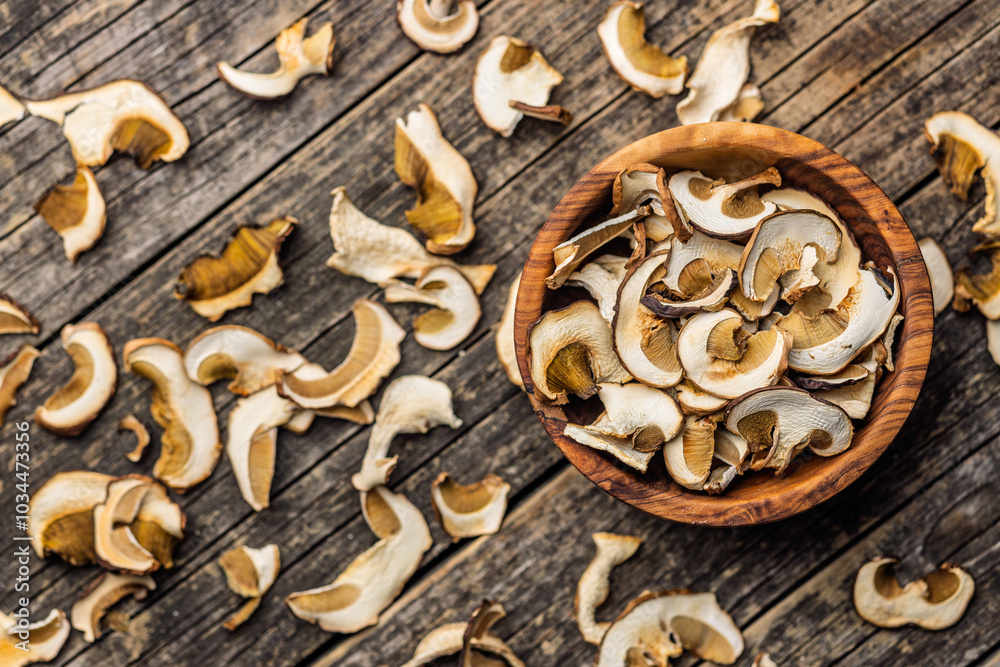 Dried porcini mushrooms. Sliced boletus in bowl on wooden table. Top view. Dried porcini mushrooms. Sliced boletus in bowl on wooden table. Top view.