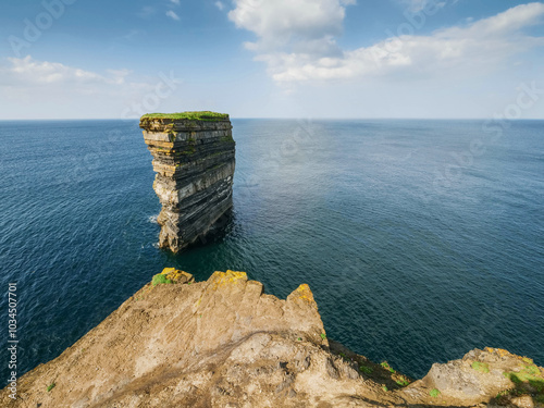 View on stunning Dun Briste sea stack in Downpatrick head, Ireland. Popular travel and tourist area with stunning scenery. Famous Irish landmark. Warm sunny day with blue cloudy sky. photo