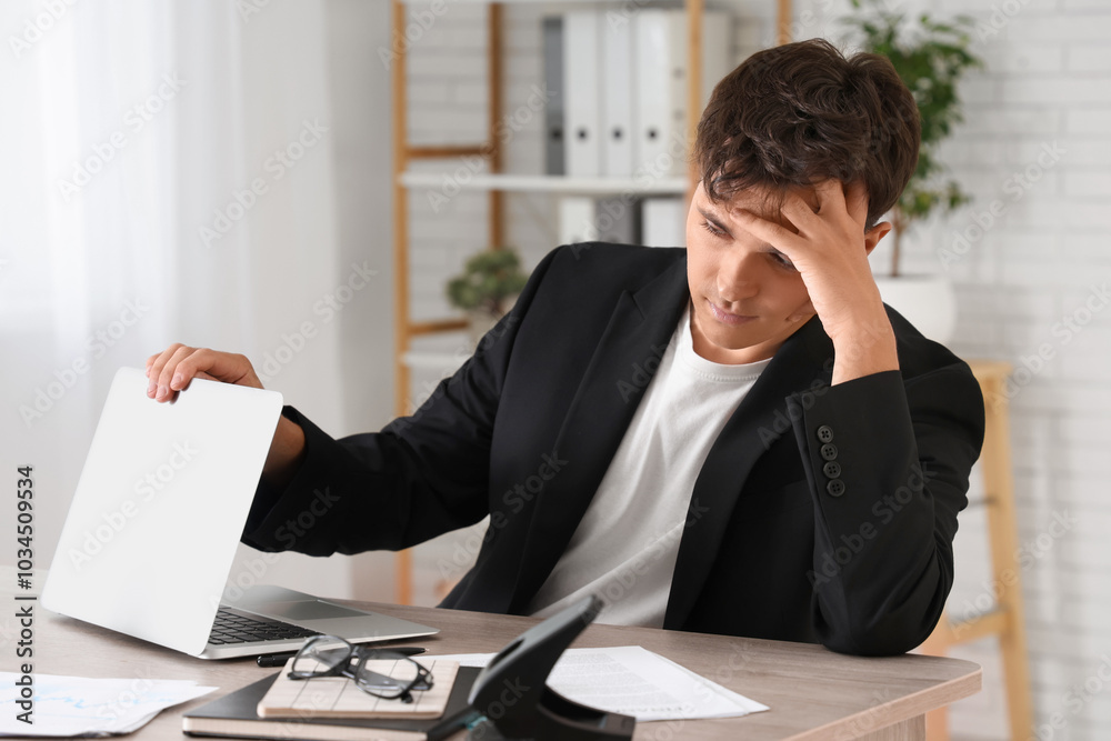 Tired businessman working with laptop at desk in office Tired businessman working with laptop at desk in office