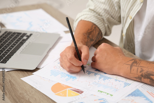 Male economist working with diagrams at table in office, closeup