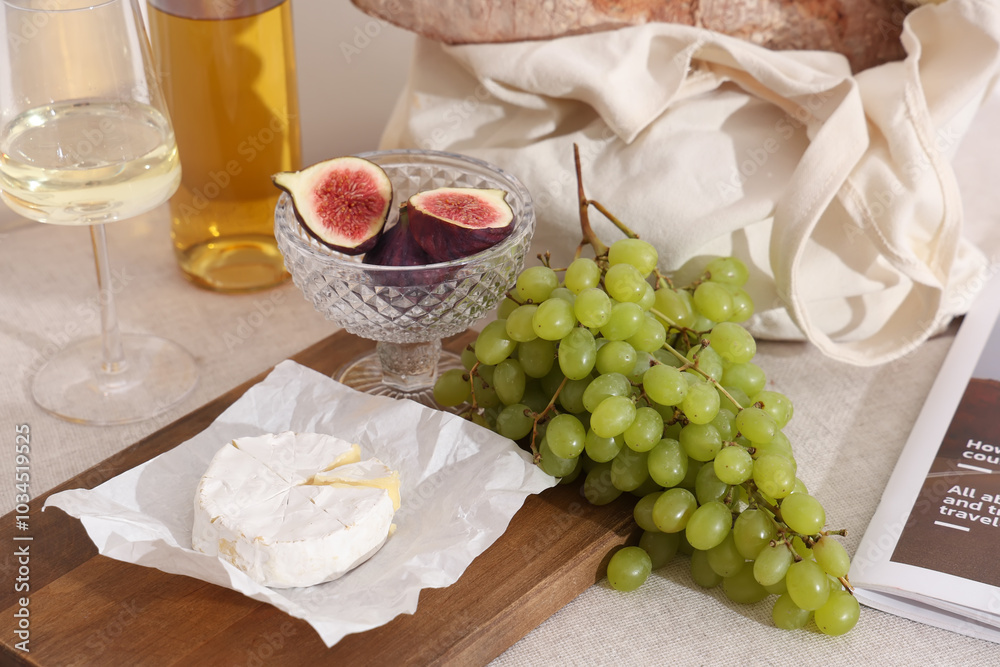 Wooden board with sweet ripe grapes, camembert cheese, figs, baguette and bottle of wine on white background Wooden board with sweet ripe grapes, camembert cheese, figs, baguette and bottle of wine on white background
