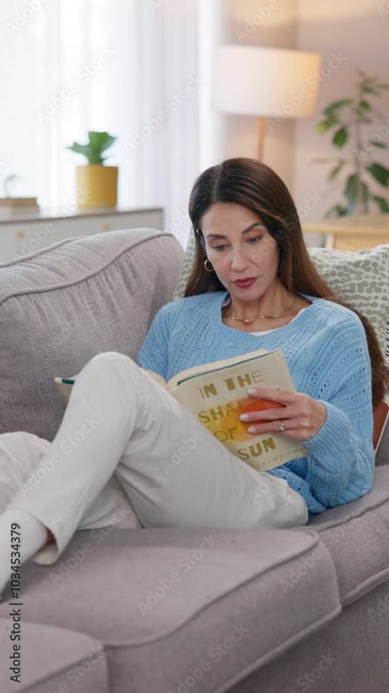 Mature woman, relax and reading book on sofa for literature hobby, and fiction story in living room. Home, comfortable and female person with novel on weekend for fantasy, learning and knowledge Mature woman, relax and reading book on sofa for literature hobby, and fiction story in living room. Home, comfortable and female person with novel on weekend for fantasy, learning and knowledge