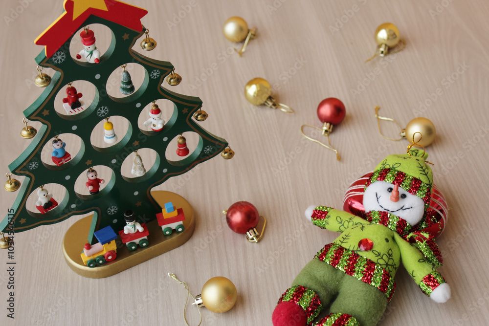 Stuffed snowman and Christmas tree toy on wood background for december holiday celebration. Xmas baubles, decoration for winter season in red and gold colors. Stuffed snowman and Christmas tree toy on wood background for december holiday celebration. Xmas baubles, decoration for winter season in red and gold colors.
