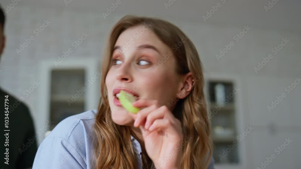 Closeup woman eating fruit home kitchen. Wife biting veggie giving to boyfriend Closeup woman eating fruit home kitchen. Wife biting veggie giving to boyfriend