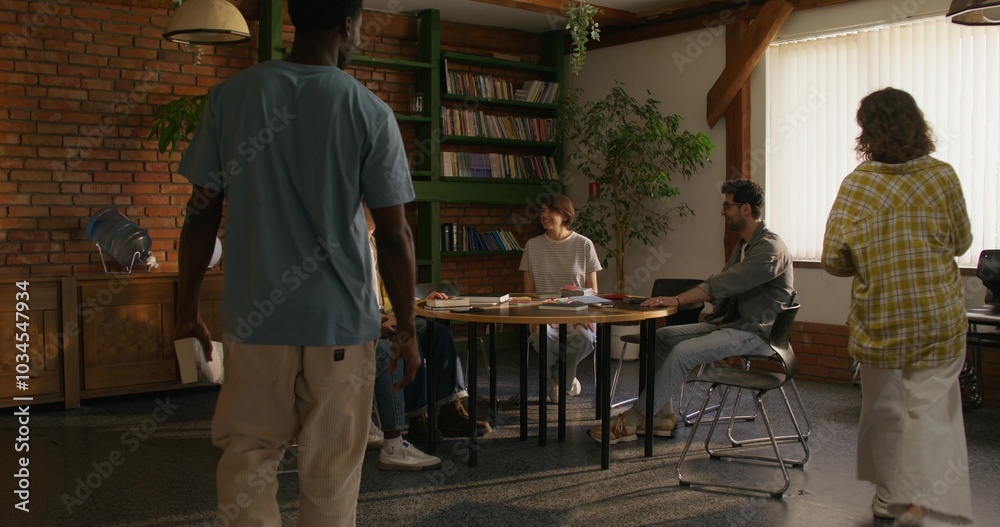 Young people of different nationalities gather at a table to study the Bible together. Stylish room, daylight Young people of different nationalities gather at a table to study the Bible together. Stylish room, daylight