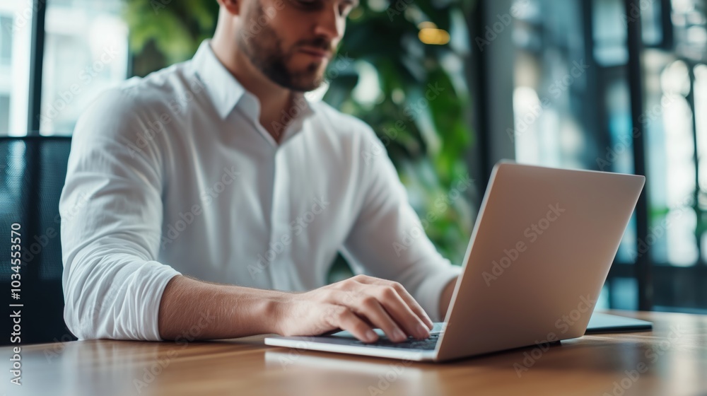 Man working on laptop in a modern office surrounded by greenery during the day. Man working on laptop in a modern office surrounded by greenery during the day.