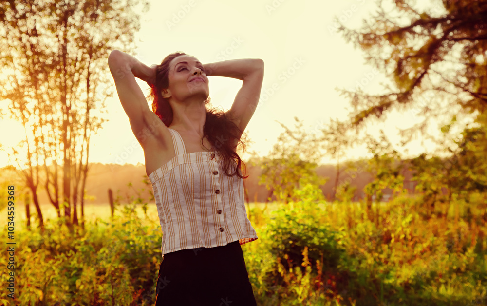 Beautiful romantic happy smiling woman posing and looking back on sunset red orange summer background among the trees. Bright lifestyle fashion portrait. Beautiful romantic happy smiling woman posing and looking back on sunset red orange summer background among the trees. Bright lifestyle fashion portrait.