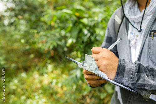 Biologist writing in a notebook the notes of his research in the middle of the rainforest, in close-up photo