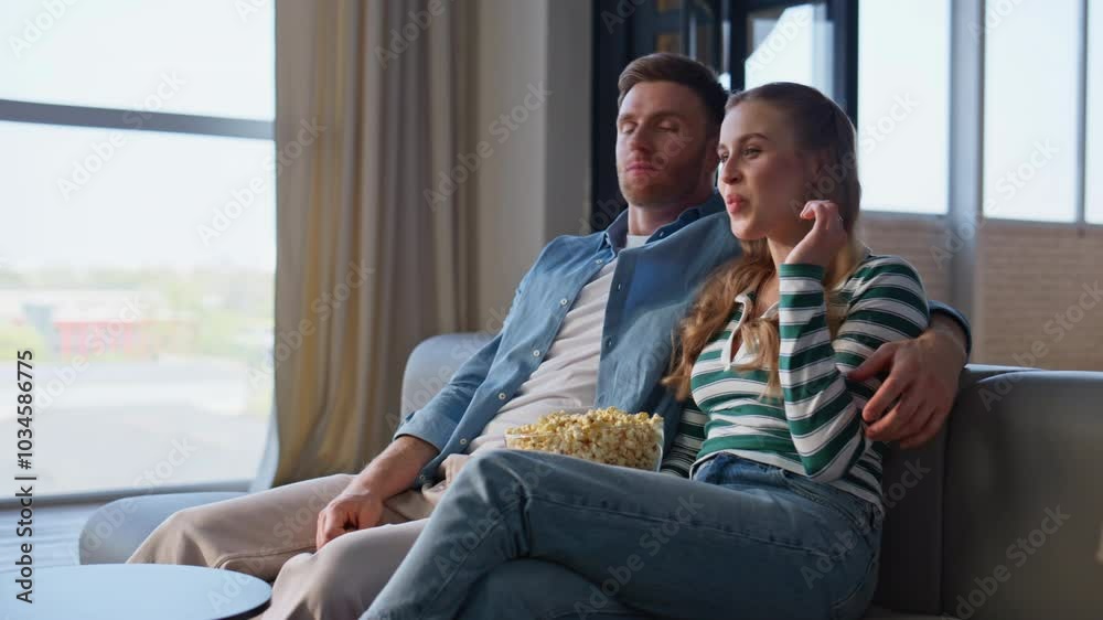 Two viewers looking film on TV at apartment sofa closeup. Couple with popcorn Two viewers looking film on TV at apartment sofa closeup. Couple with popcorn
