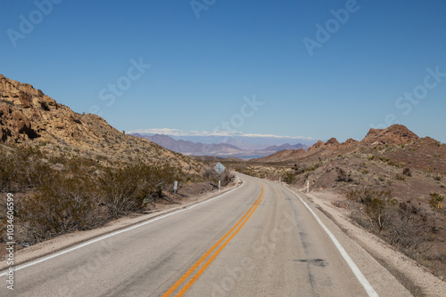 Two lane road through the desert with mountains in background