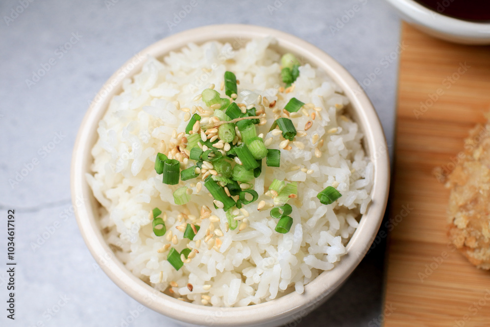 Steamed rice with black sesame seeds and spring onion in ceramic bowl on table. Japanese and Asia eat with food Steamed rice with black sesame seeds and spring onion in ceramic bowl on table. Japanese and Asia eat with food