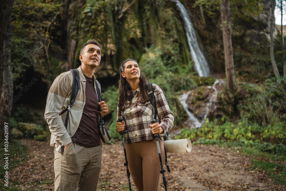 hiker couple explore forest around waterfall with hiking sticks hiker couple explore forest around waterfall with hiking sticks