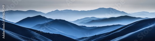 A misty mountain range with a cool blue hue creates a sense of peace and tranquility.