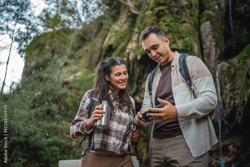 hiker couple backpackers stand in front waterfall and use cellphone hiker couple backpackers stand in front waterfall and use cellphone