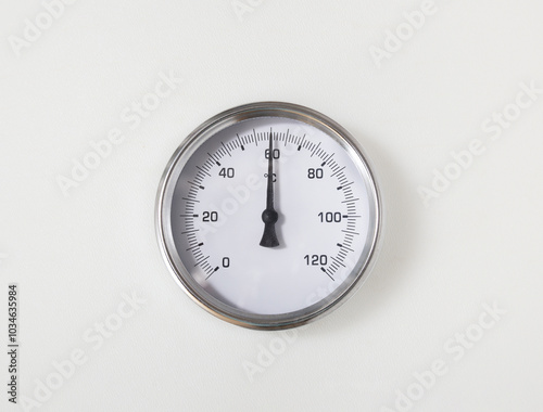 Thermometer of water heater in boiler room of in building. Close up of hot water temperature gauge with arrow on 60 Celsius. Safety inspection on hot water heater or heating systems. Selective focus.