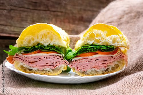 Italian mortadella bologna sandwich with arugula, tomato and cheese on ciabatta bread photo