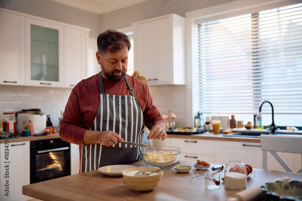 Mature man preparing dough while baking in kitchen. Mature man preparing dough while baking in kitchen.