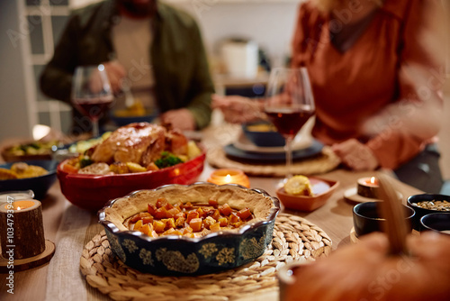 Thanksgiving pumpkin pie on dining table with couple in background.