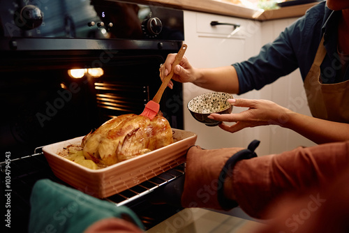 Photography Close up of couple basting roast turkey while making Thanksgiving dinner
