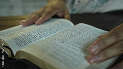 man open the book of the bible and read it on a wooden table daytime