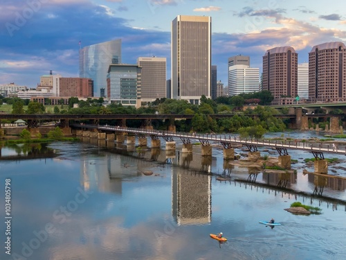 People kayaking and the T. Tyler Potterfield Memorial Bridge crossing the James River. In the distance is the downtown city skyline.  Richmond, Virginia, United States.