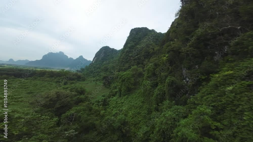 Drone captures lush hills and tranquil waters at Blue Lagoon in Vang Vieng, Laos, with misty peaks in the background Drone captures lush hills and tranquil waters at Blue Lagoon in Vang Vieng, Laos, with misty peaks in the background