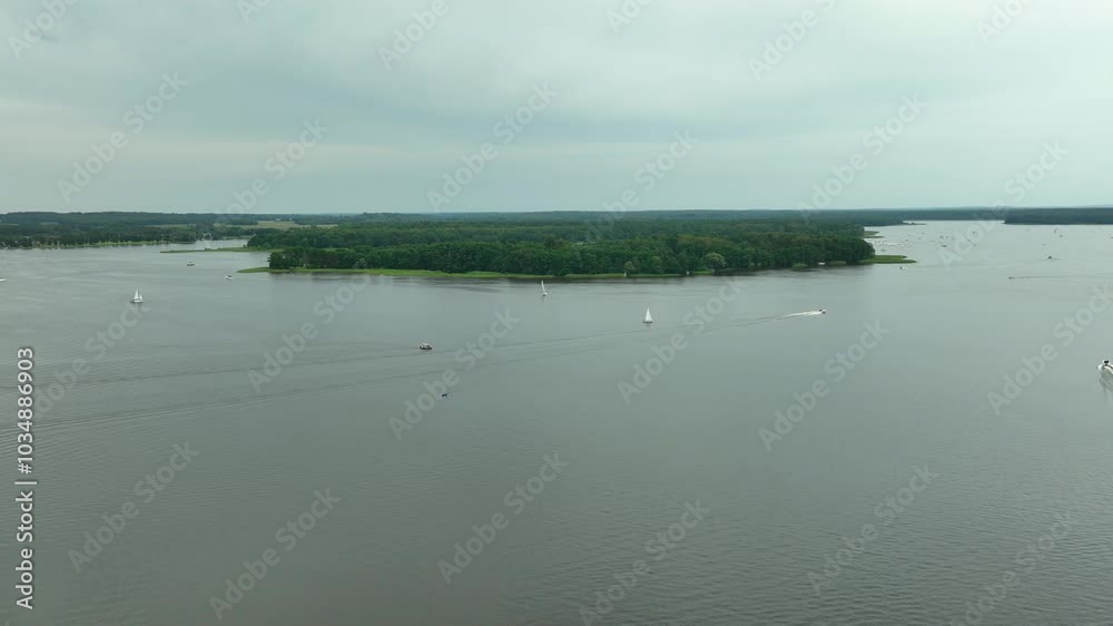 Aerial shot of a serene lake with sailboats and forested shores, overcast sky - Siemiany, Jeziorak Aerial shot of a serene lake with sailboats and forested shores, overcast sky - Siemiany, Jeziorak