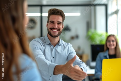 Young Caucasian businessman smiling and reaching out for a handshake in a modern office setting during the day