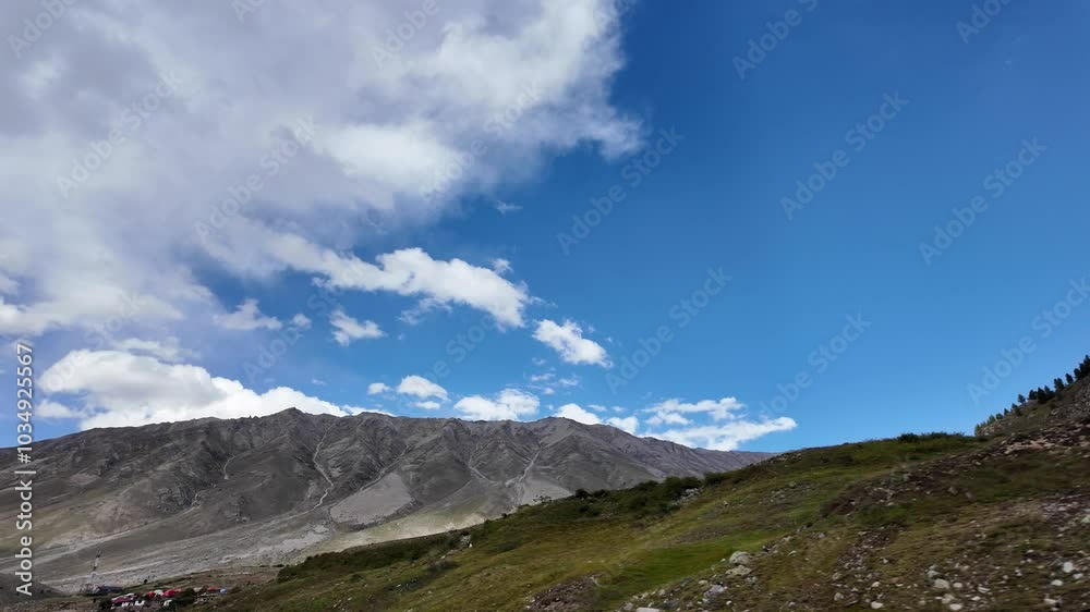 Stunning View Towering Trees and Cozy Houses Nestled on Majestic Green Mountains, with a Remote Signal Tower,Vibrant Blue Sky with Fluffy Clouds, Surrounded by Green Meadow