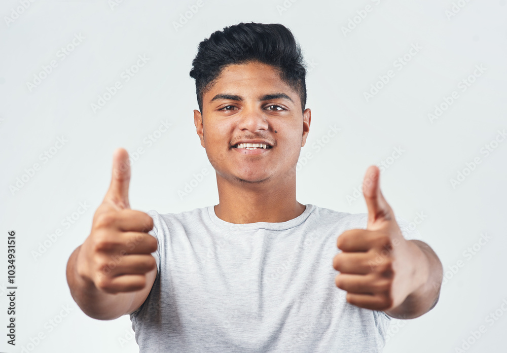 Indian, portrait and happy man with thumbs up for winning, good job or well done on a white studio background. Young, male person or gen z model with smile, like emoji or yes sign for OK or great Indian, portrait and happy man with thumbs up for winning, good job or well done on a white studio background. Young, male person or gen z model with smile, like emoji or yes sign for OK or great