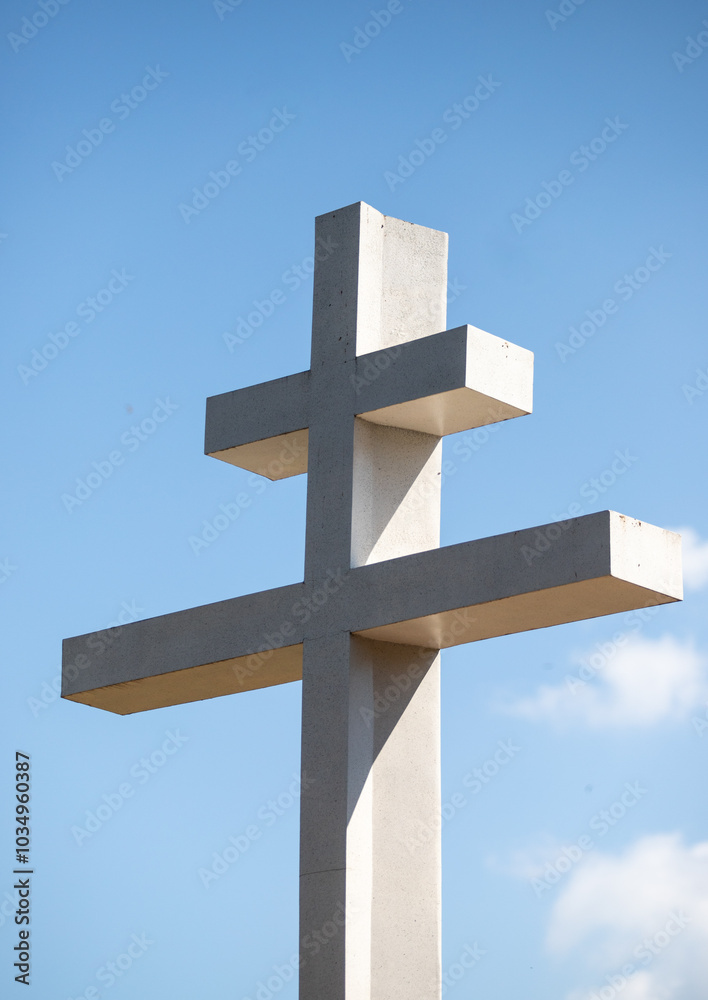 A white cross is standing tall in a blue sky A white cross is standing tall in a blue sky