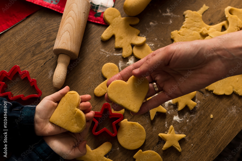 Mother and daughter holding in hands heart shaped Christmas cookies ready for baking, close up