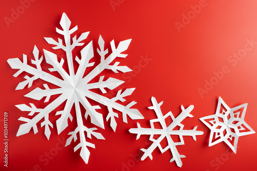 white paper cut out snowflakes in red background. Empty space for copy space. winter or christmas theme background. selective focus.