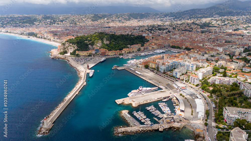 Aerial view of Nice, France, featuring the stunning coastline with turquoise waters, the bustling port filled with yachts, and the vibrant cityscape stretching along the Mediterranean. Aerial view of Nice, France, featuring the stunning coastline with turquoise waters, the bustling port filled with yachts, and the vibrant cityscape stretching along the Mediterranean.