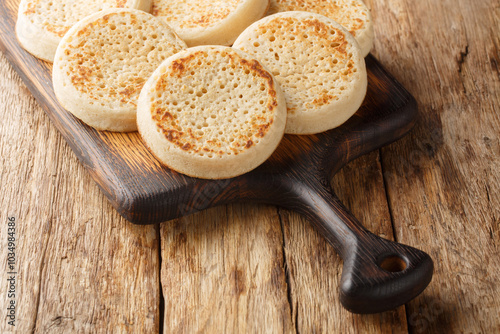 Close up of fresh golden crumpets on the wooden board on the table. Horizontal