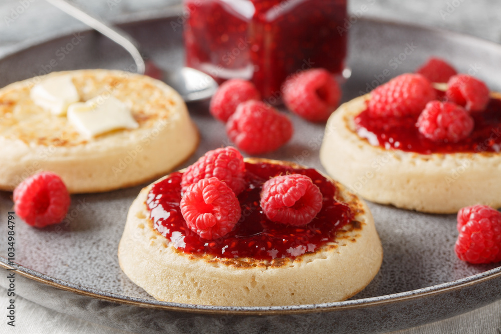 British Crumpets breakfast with butter and raspberry jam closeup on the plate on the table. Horizontal British Crumpets breakfast with butter and raspberry jam closeup on the plate on the table. Horizontal