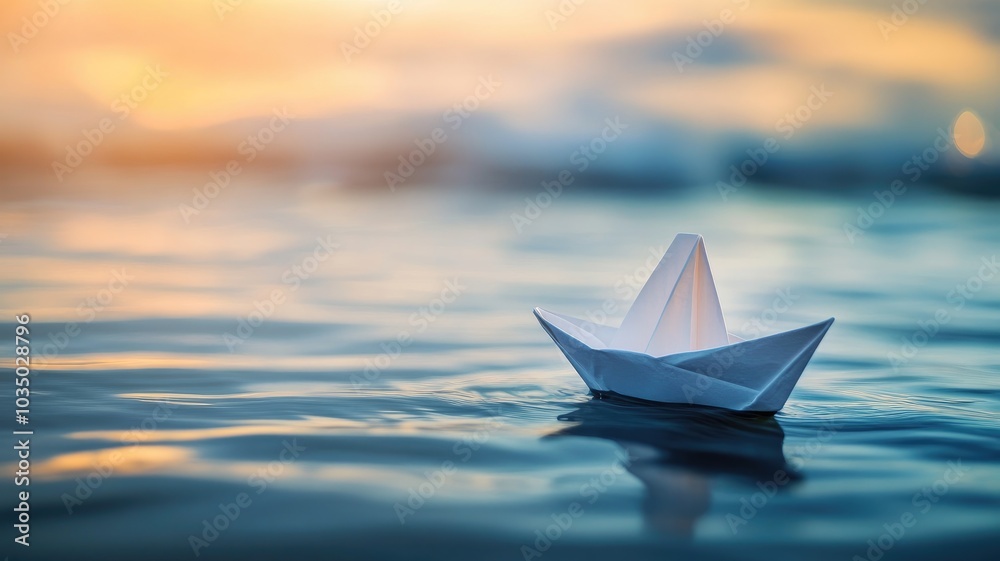 Obraz premium White origami boat floating on calm sea during sunrise