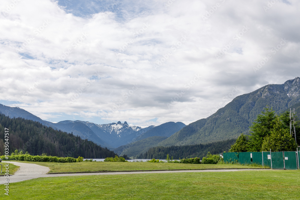 A scenic view of the Capilano River Regional Park with lush forests, snow-capped mountains, and a clear path leading to the reservoir, perfect for outdoor activities and nature walks in Vancouver A scenic view of the Capilano River Regional Park with lush forests, snow-capped mountains, and a clear path leading to the reservoir, perfect for outdoor activities and nature walks in Vancouver