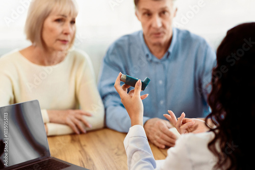 Doctor Holding Blue Asthma Inhaler For Treatment COPD Diseases For Senior Couple Patients