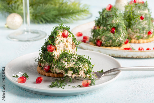 Portioned tuna pate on cracker decorated with dill and pomegranate seeds. Christmas appetizer in shape of Christmas tree.