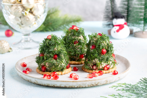Portioned tuna pate on cracker decorated with dill and pomegranate seeds. Christmas appetizer in shape of Christmas tree.