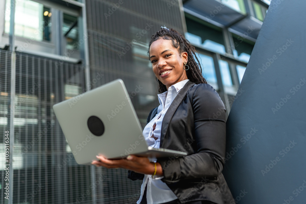Modern latin businesswoman working using laptop outside a financial building Modern latin businesswoman working using laptop outside a financial building