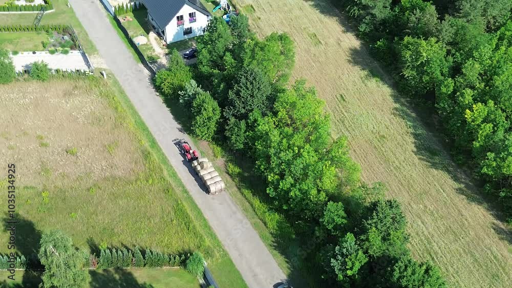 Red tractor delivering fresh hay bales viewed from above Red tractor delivering fresh hay bales viewed from above