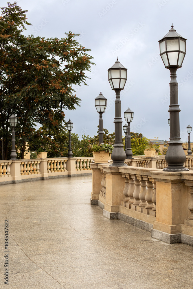 Fototapeta premium city autumn street after the rain with yellow balustrade and lanterns and autumn trees on a cloudy autumn day after the rain