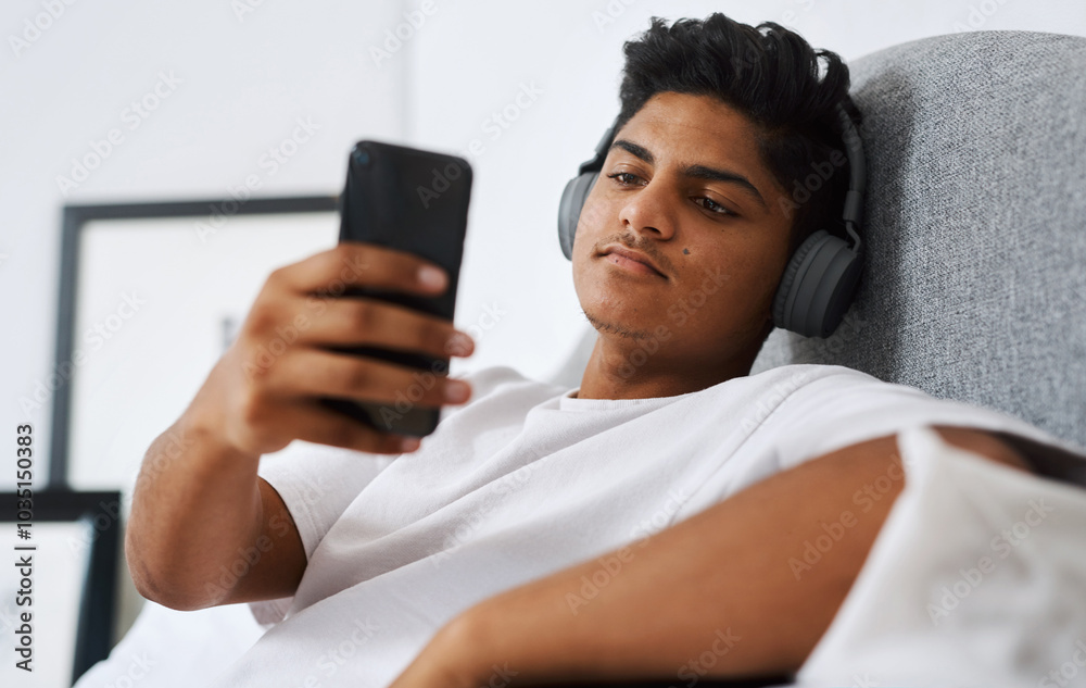 Teenager, headphones and person with phone on bed for internet, connection and listening to song. Calm, boy and relax with technology at home for streaming, audio and update of music playlist Teenager, headphones and person with phone on bed for internet, connection and listening to song. Calm, boy and relax with technology at home for streaming, audio and update of music playlist