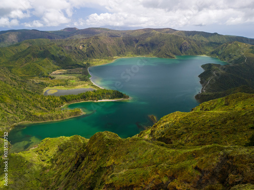 Aerial view of the breathtaking Miradouro da Lagoa do Fogo with a serene lake surrounded by lush green mountains and a vibrant sky, Agua de Alto, Portugal. photo