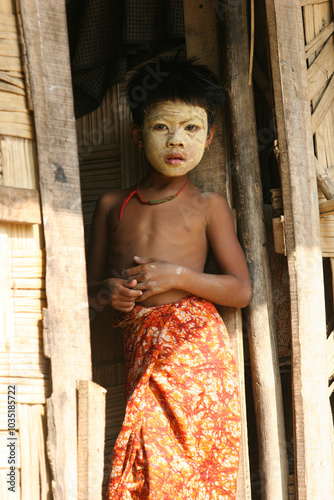 Bangladeshi tribal child standing on the doorway of his house with face makeup  photo