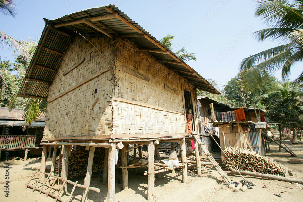 Traditional bamboo and wood made house of Bangladeshi tribal people, a chakma kid is standing on the doorstep of the house Traditional bamboo and wood made house of Bangladeshi tribal people, a chakma kid is standing on the doorstep of the house