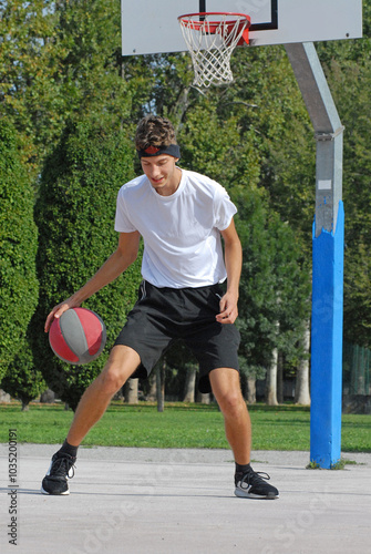 Boy playing basket ball on outdoors basket court.