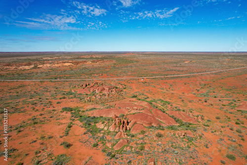 Aerial view of arid desert landscape with boulders and N W Coastal Highway under a vast sky, Nanutarra, Australia. photo